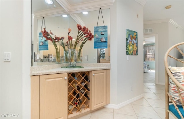 bar featuring baseboards, light tile patterned floors, indoor bar, visible vents, and ornamental molding