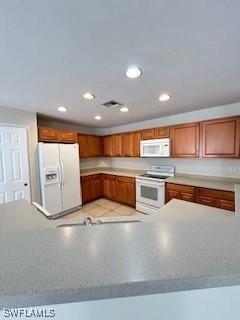 18301 Pine Nut Ct, Lehigh Acres, FL 33972 - kitchen with white appliances, recessed lighting, and brown cabinetry