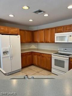 18301 Pine Nut Ct, Lehigh Acres, FL 33972 - kitchen featuring white appliances, brown cabinets, visible vents, and recessed lighting