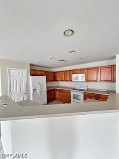 18301 Pine Nut Ct, Lehigh Acres, FL 33972 - kitchen featuring light countertops, brown cabinets, a peninsula, and white appliances