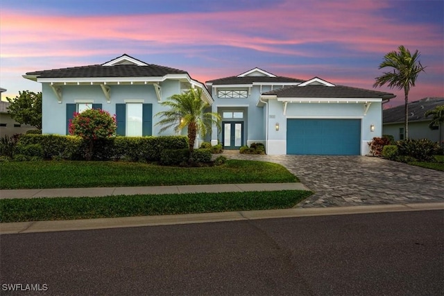 view of front of home with stucco siding, decorative driveway, a garage, and french doors