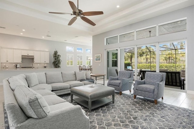 living area featuring a towering ceiling, recessed lighting, a raised ceiling, and ceiling fan