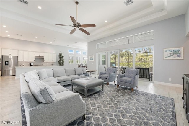 living area featuring a towering ceiling, visible vents, and a raised ceiling