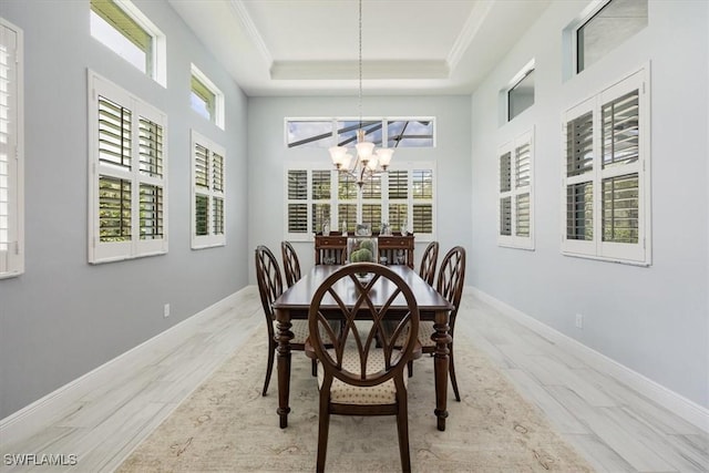 dining area featuring a chandelier, wood finished floors, baseboards, and a tray ceiling