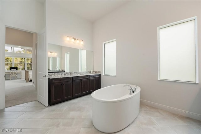bathroom with vanity, baseboards, a freestanding tub, and tile patterned floors