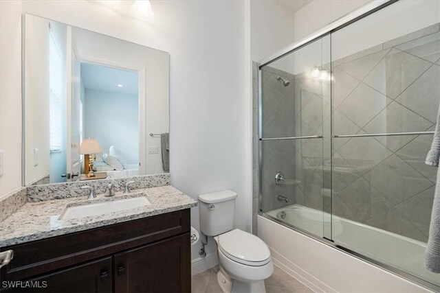bathroom with toilet, vanity, shower / bath combination with glass door, and baseboards