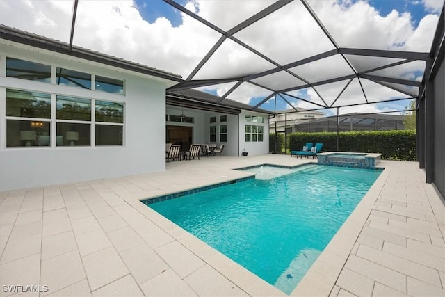 view of pool featuring glass enclosure, a patio area, and a pool with connected hot tub