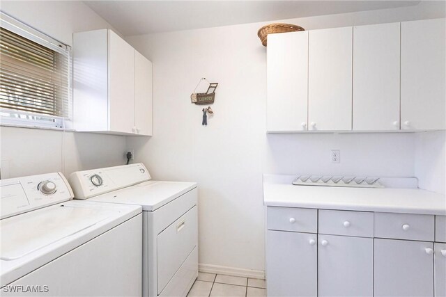 clothes washing area with separate washer and dryer, baseboards, light tile patterned floors, and cabinet space