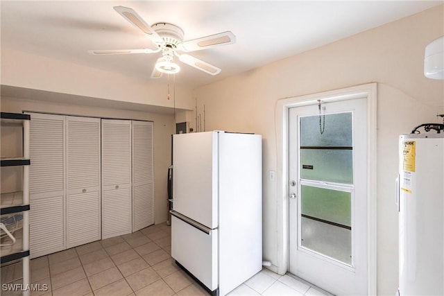 kitchen with water heater, a ceiling fan, light tile patterned flooring, and freestanding refrigerator