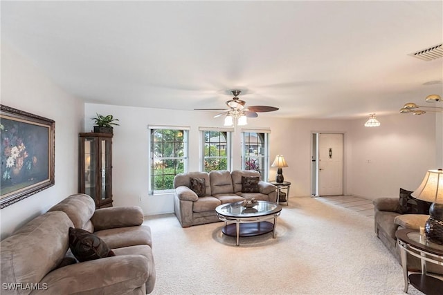 living room featuring visible vents, a ceiling fan, and light colored carpet
