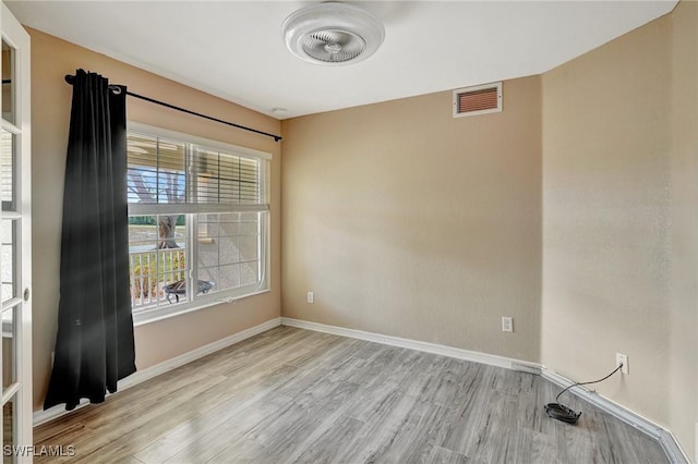 empty room with baseboards, visible vents, and wood finished floors