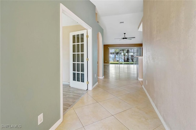 corridor featuring light tile patterned flooring, baseboards, and visible vents