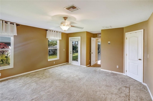 carpeted empty room featuring baseboards, ceiling fan, and visible vents