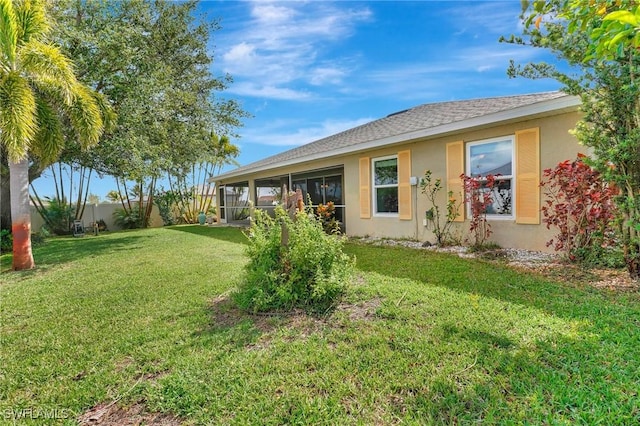 back of property with a lawn, fence, a sunroom, and stucco siding