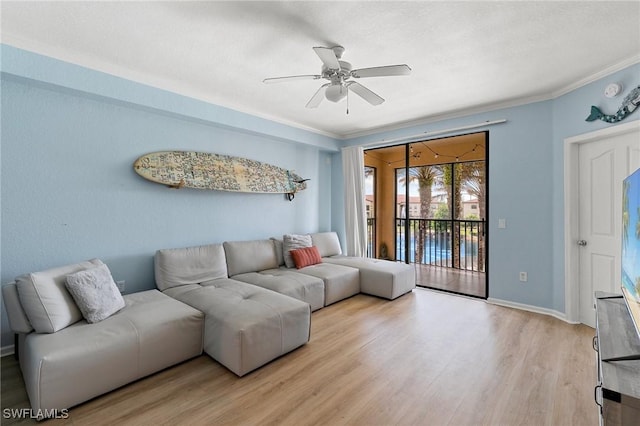living area featuring light wood-style floors, ornamental molding, baseboards, and ceiling fan