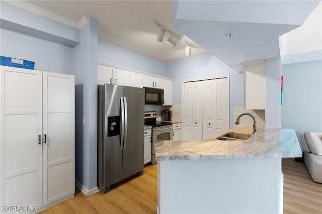 kitchen featuring a sink, light wood-style floors, stainless steel appliances, a peninsula, and white cabinetry