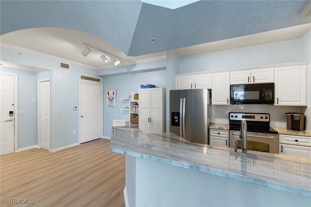 kitchen with light stone countertops, light wood-style floors, rail lighting, and appliances with stainless steel finishes