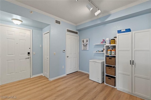clothes washing area featuring light wood-type flooring, visible vents, laundry area, and crown molding