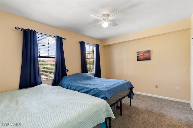 carpeted bedroom with ceiling fan and baseboards