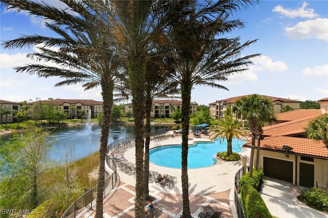 pool featuring a patio area, a water view, and a residential view