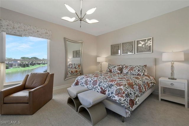 bedroom featuring carpet floors, a water view, baseboards, and a notable chandelier