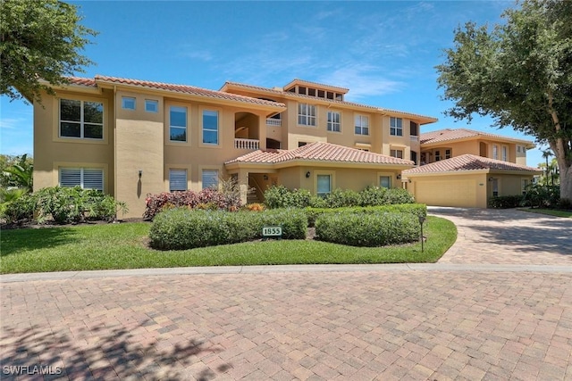 mediterranean / spanish-style house featuring a garage, stucco siding, decorative driveway, and a tile roof