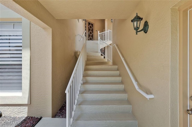 stairway featuring a textured wall