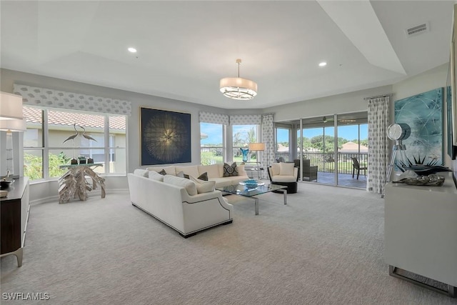 carpeted living room with a raised ceiling, a chandelier, recessed lighting, baseboards, and visible vents
