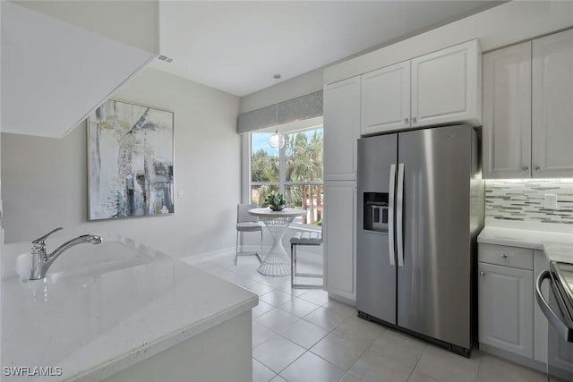 kitchen featuring light tile patterned flooring, a sink, range, decorative backsplash, and stainless steel refrigerator with ice dispenser
