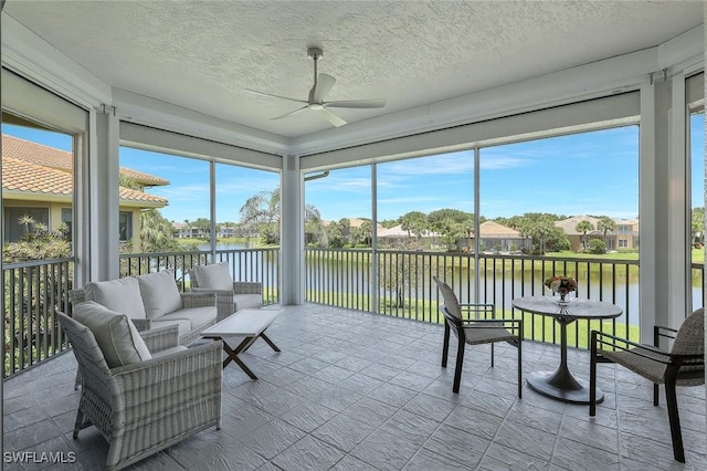 sunroom / solarium featuring a water view, ceiling fan, outdoor lounge area, and a residential view