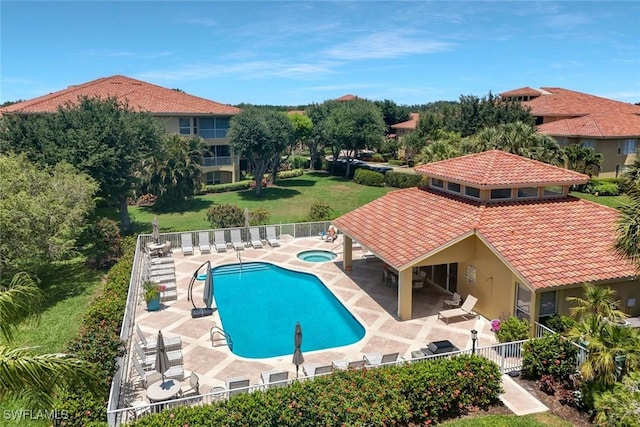 community pool with a patio area, a hot tub, and fence