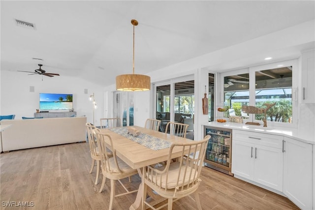 dining room with light wood-type flooring, vaulted ceiling, visible vents, a ceiling fan, and beverage cooler