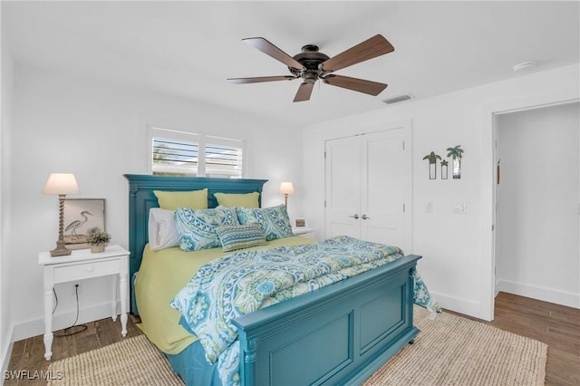 bedroom featuring baseboards, visible vents, a ceiling fan, wood finished floors, and a closet