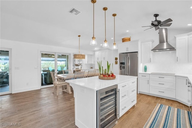 kitchen featuring beverage cooler, visible vents, high end refrigerator, stovetop, and wall chimney exhaust hood