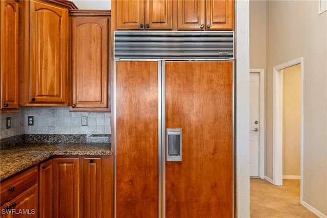 2817 La Mancha Ct, Punta Gorda, FL 33950 - kitchen with paneled fridge, backsplash, brown cabinets, and dark stone countertops