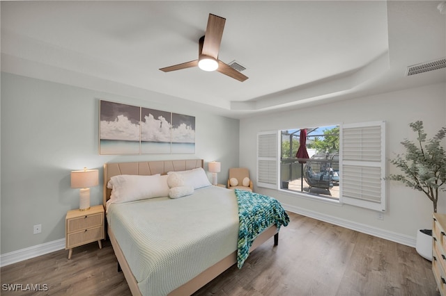 bedroom with a raised ceiling, baseboards, and wood finished floors