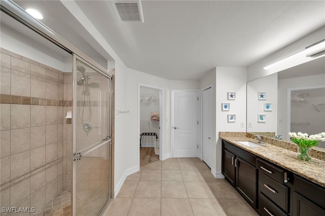 full bath with a shower stall, vanity, a spacious closet, and tile patterned flooring