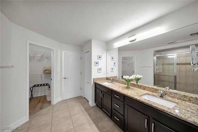 full bathroom featuring a stall shower, a spacious closet, double vanity, and tile patterned flooring