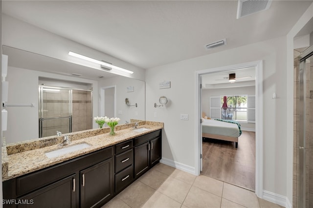 ensuite bathroom featuring a stall shower, tile patterned flooring, baseboards, and double vanity