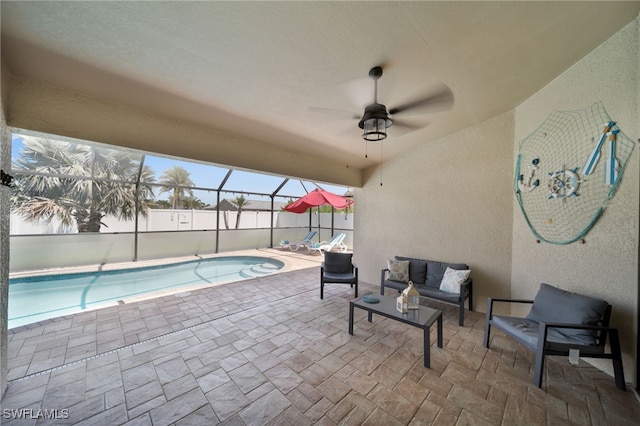 view of pool with a patio, outdoor lounge area, glass enclosure, and a ceiling fan