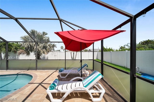 view of pool with a patio area, glass enclosure, and fence