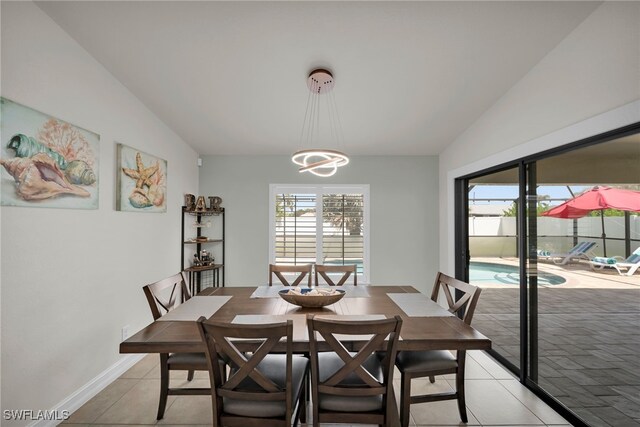 dining area featuring lofted ceiling, light tile patterned floors, and a chandelier