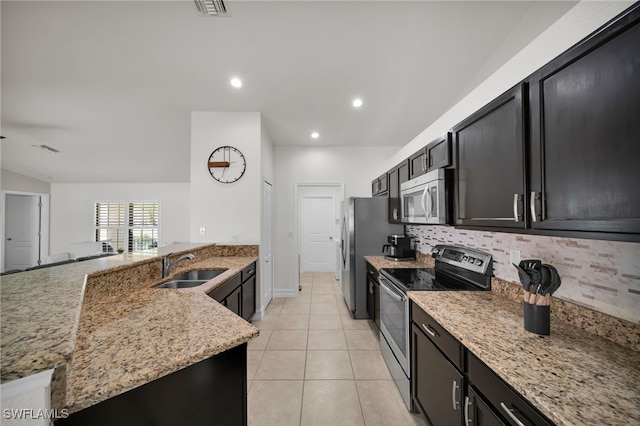 kitchen with appliances with stainless steel finishes, light stone counters, a sink, backsplash, and recessed lighting