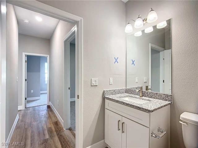 3309 55th St W, Lehigh Acres, FL 33971 - bathroom with toilet, vanity, wood finished floors, and baseboards