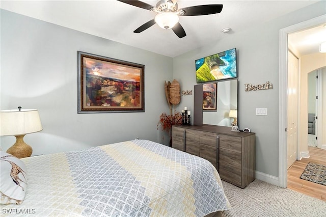 1259 Carpazi Ct Unit 302, Naples, FL 34105 - bedroom featuring light wood-style floors, arched walkways, baseboards, light carpet, and a ceiling fan