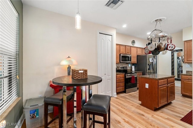 1259 Carpazi Ct Unit 302, Naples, FL 34105 - kitchen featuring tasteful backsplash, visible vents, stainless steel appliances, light wood-style floors, and a center island