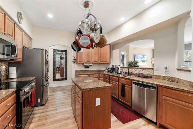 1259 Carpazi Ct Unit 302, Naples, FL 34105 - kitchen with a sink, stainless steel appliances, light wood-style floors, a kitchen island, and arched walkways