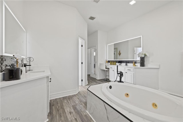 3007 8th St W, Lehigh Acres, FL 33971 - full bath with two vanities, wood finished floors, a jetted tub, and baseboards