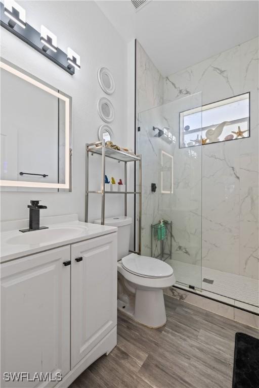 3007 8th St W, Lehigh Acres, FL 33971 - full bath with toilet, a marble finish shower, vanity, and wood finished floors