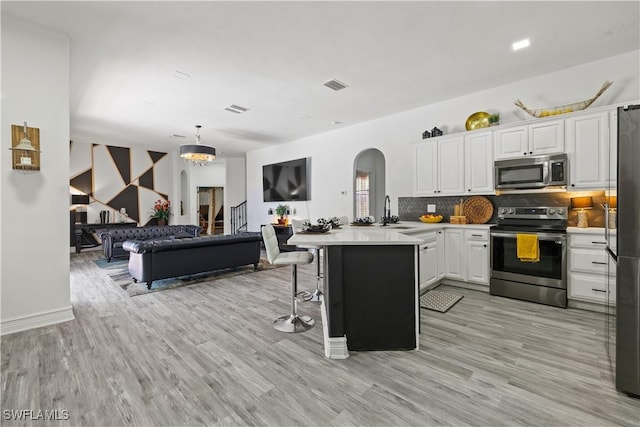 3007 8th St W, Lehigh Acres, FL 33971 - kitchen with appliances with stainless steel finishes, arched walkways, a sink, a peninsula, and white cabinetry
